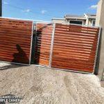 Wooden slatted Gate and fence erected on a paved driveway