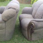 Two light gray couches newly upholstered with thick padding and wooden frame, standing on a green lawn