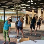 Clients standing up being over to the right with their right arm over their heads while exercising with Pilates coach Leonard Lubbe in Sunwich Port