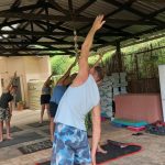 Pilates coach Leonard Lubbe stands in front of his class stretching his left hand out straight and over his head