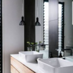 Double hand basins on a wooden vanity cabinet behind a large mirror