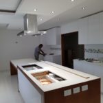 Carpenter installing kitchen units in white kitchen