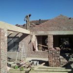 A builder standing on the roof of a house being constructed