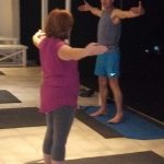 A lady standing inside a studio at night doing Pilates with fitness coach Leonard on the South Coast KN