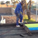 Nickluk Project handyman on roof using torch for waterproofing building