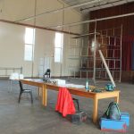 large room with a fold up table and various machinery and material for sewing