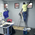 Man on ladder painting interior wall grey