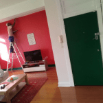 Man on ladder inside room painting wall red