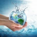 Hands holding a bowl of water with green earth globe inside it