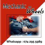 Red and white poster with picture of a man's hands working on a car engine to advertise mechanic on Wheels in Durban North