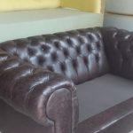 Brown leather couch with buttoned back and thick arm rests which was reupholstered by the artisans from Indlu Yeagagu