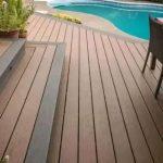 Slats of wood laid down as a wooden deck with stairs going to a door next to a swimming pool