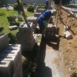 Men in blue overhauls laying foundations to erect brick walls