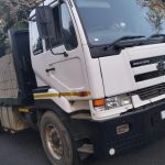 White flat bed truck standing on the road with a load of building blocks on the back