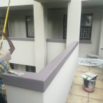 Outdoor corridoirsw of a large building being painted two shades of grey by Indlu Yegagu Iyanetha Primary Cooperative building construction Durban