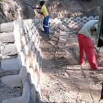 Angled retaining wall being built with white bricks by Indlu Yegagu Iyanetha Primary Cooperative building construction Durban staff