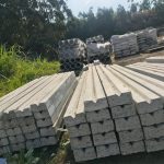 Lintels for building lie in a neat pile in the yard with batches of pillars in batches behind the lintels